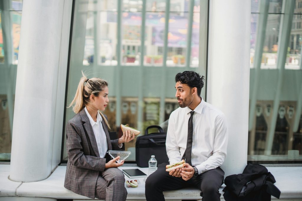 Two professionals in a modern office enjoying a lunch break and engaging in conversation